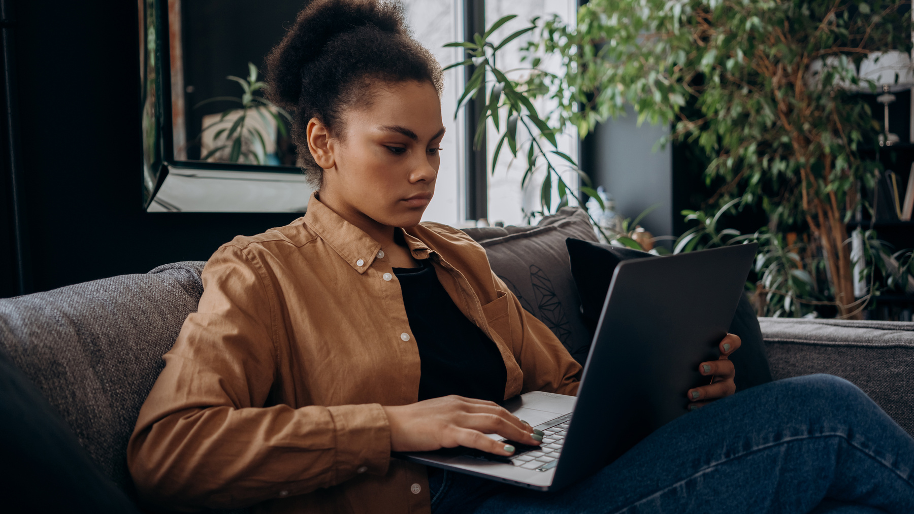 A Woman Sitting On Gray Sofa Using Laptop